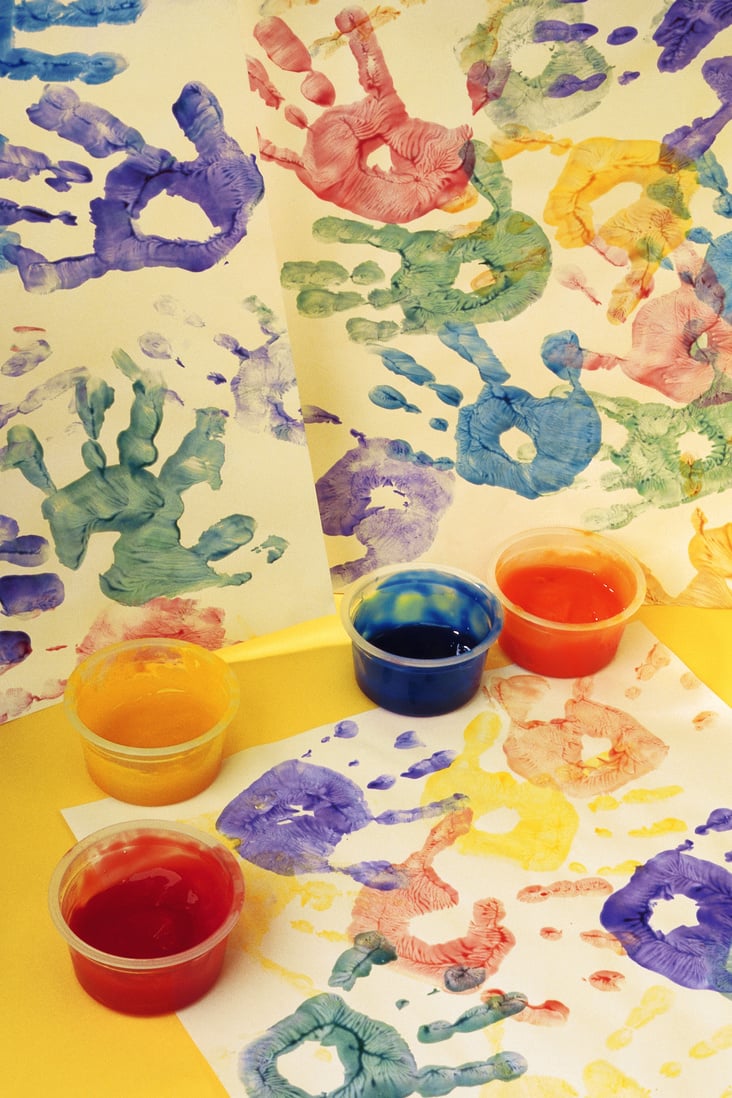 Colorful handprints and cups of paint