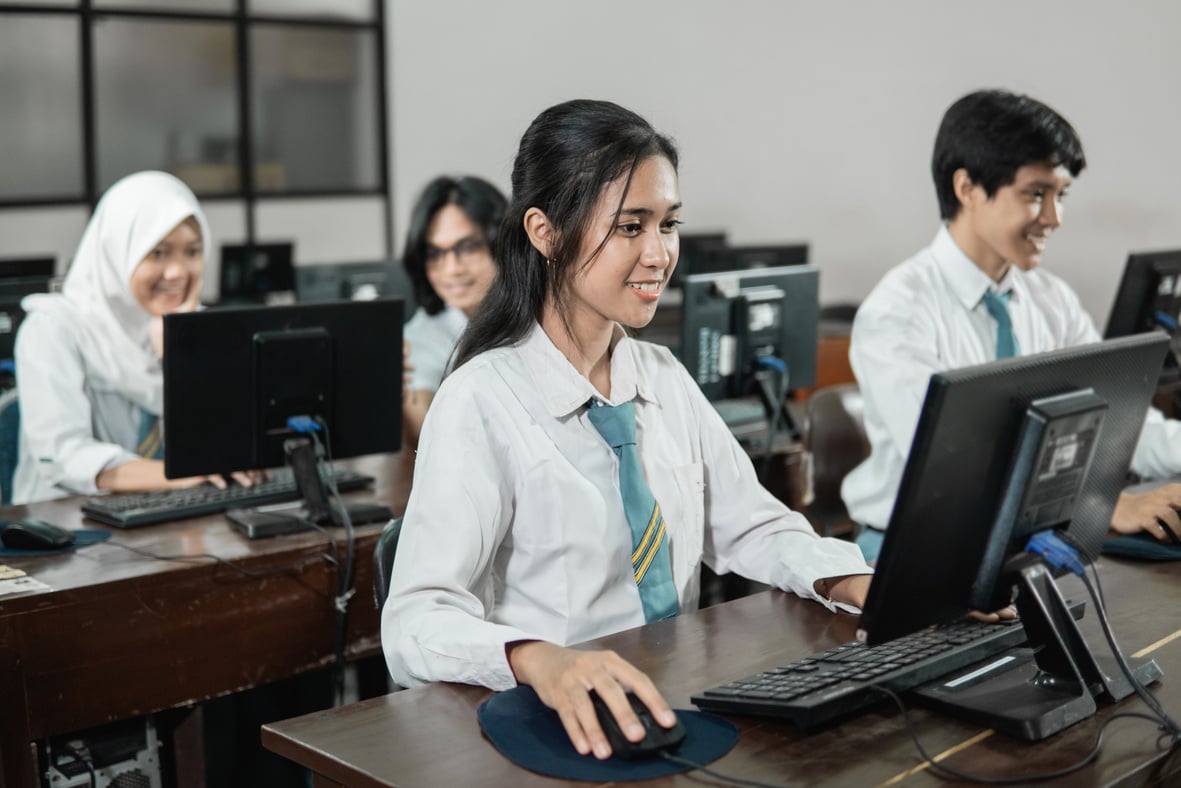 Indonesian Female High School Students Smile While Using a Computer PC